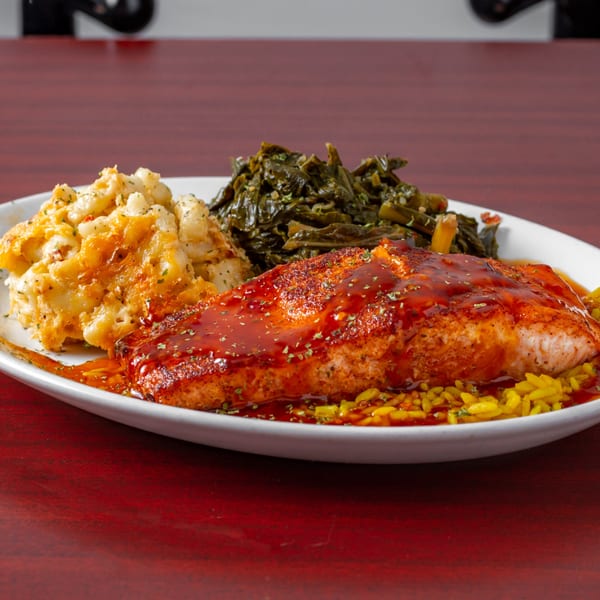 Soul food plate with BBQ salmon, yellow rice, macaroni and cheese, and collard greens.